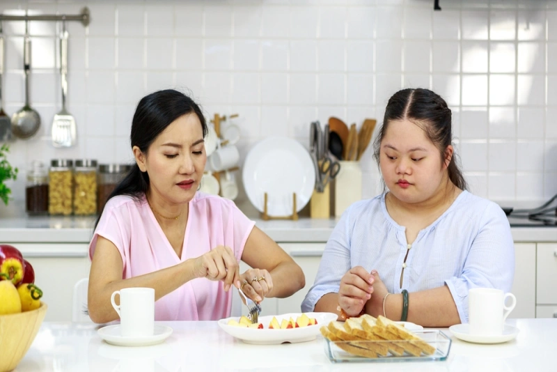 Support worker and disabled girl having breakfast