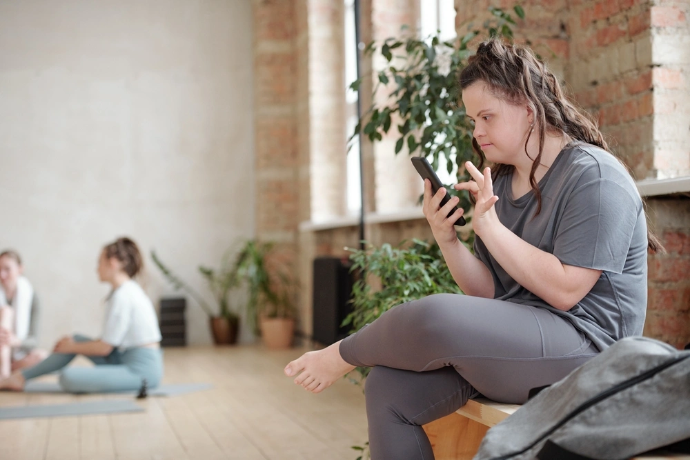 Disabled woman with down syndrome on mobile phone to contact Ultimate Gentle Heart