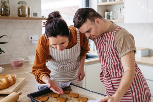 Disabled man with down syndrome baking with support worker in kitchen